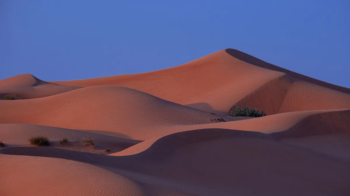 A tranquil view of desert sand dunes under a twilight sky, showcasing natural beauty.